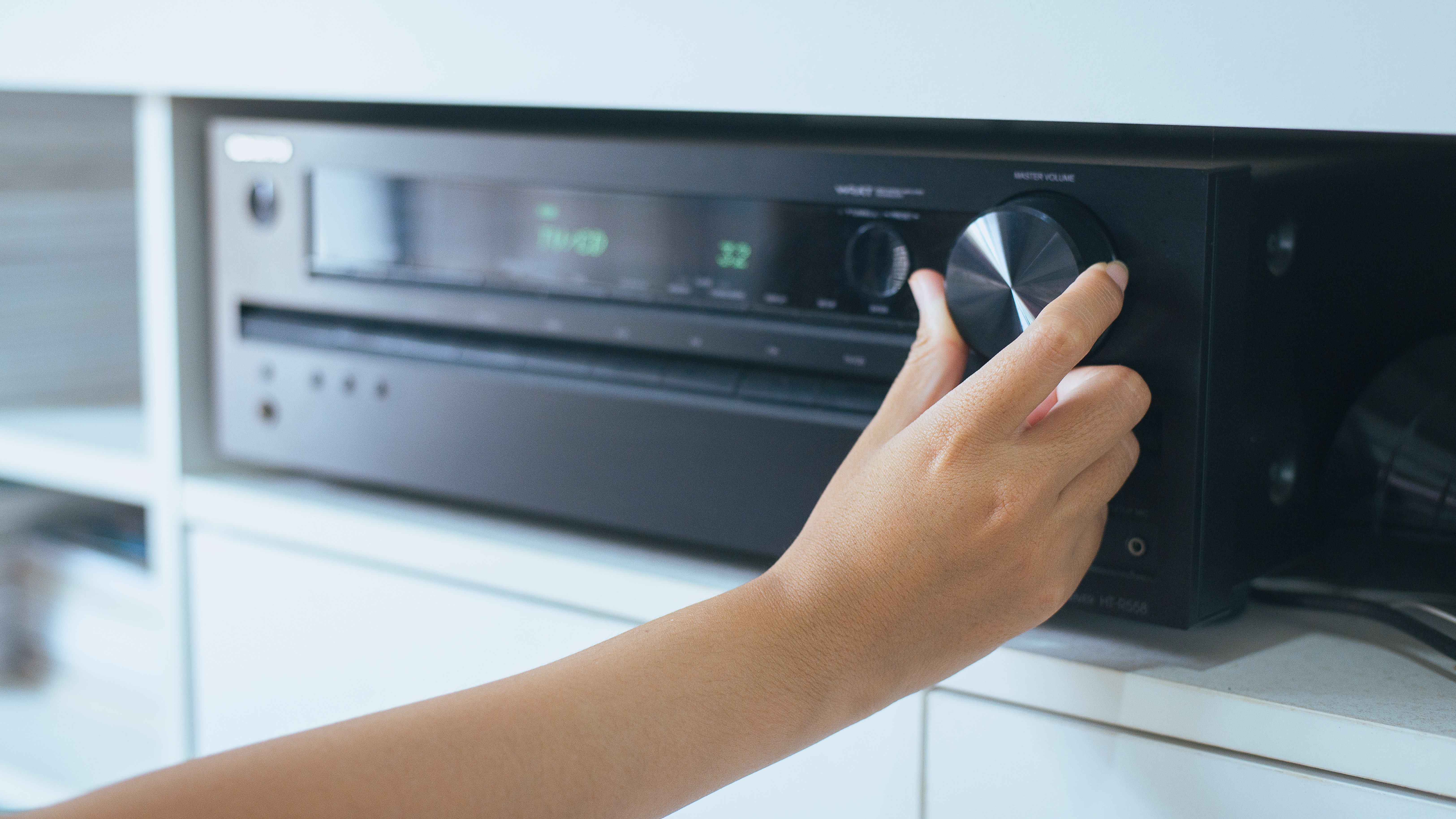 Woman's hand turning knob on AV receiver