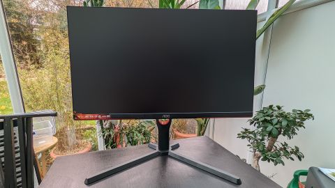 A black AOC Gaming 25G3ZM/BK monitor with red detail sitting on a desk