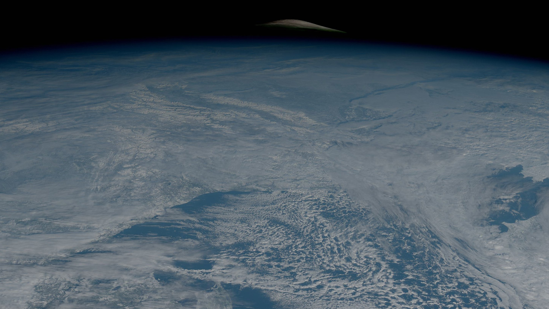 The moon's crown peeks above Earth a day before total lunar eclipse (satellite photo)