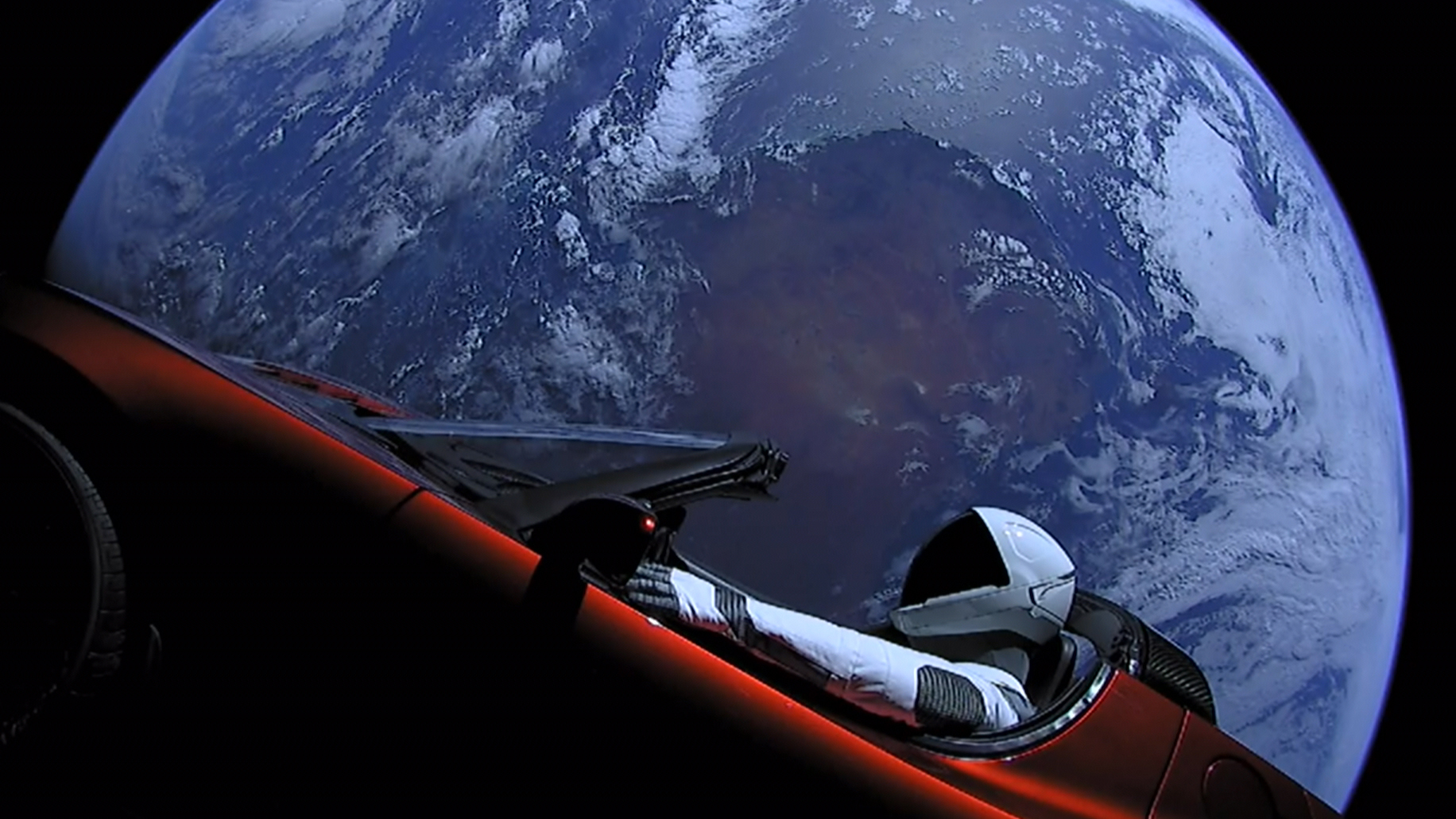 Image of Tesla Roadster and Starman dummy astronaut in space, looking down on the Earth
