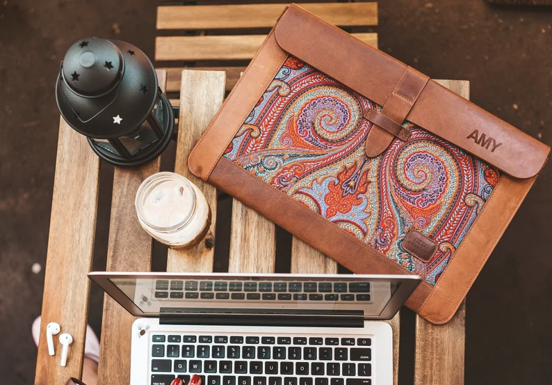 A leather MacBook sleeve on a rustic desk