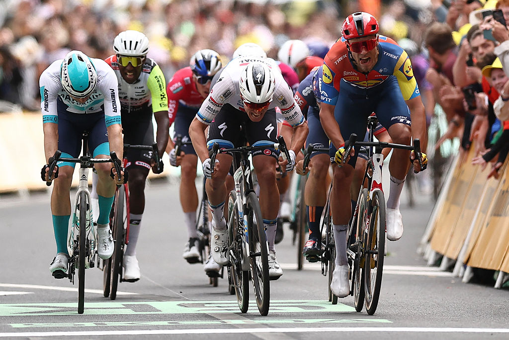 Soudal Quick-Step team's Belgian rider Tim Merlier (C) sprints to the finish line to win ahead of Lidl - Trek team's Italian rider Jonathan Milan (R) placing second and Bahrain - Victorious team's German rider Phil Bauhaus (L) placing third in the 3rd stage of the 112th edition of the Tour de France cycling race, 178.3 km between Valenciennes and Dunkerque (Dunkirk), Northern France, on July 7, 2025. (Photo by Anne-Christine POUJOULAT / AFP) (Photo by ANNE-CHRISTINE POUJOULAT/AFP via Getty Images)