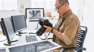 A photographer looks at his camera while using one of the best monitors for photo editing
