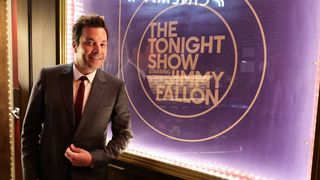 Jimmy Fallon next to The Tonight Show 10th Anniversary poster