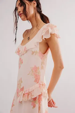 a model wears a pink floral midi dress with ruffles