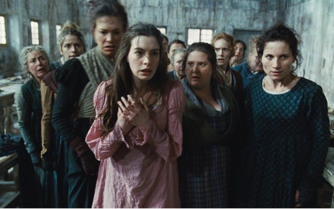 Anne Hathaway and a group of women looking bedraggled and desperate