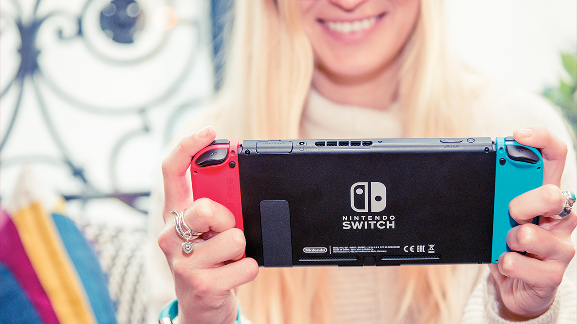 A photo of a young woman playing a Nintendo Switch games console
