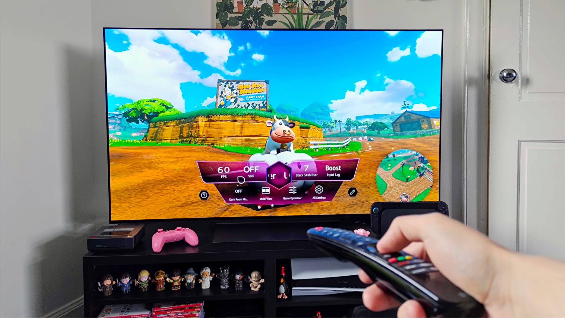 Hand holding remote in front of LG OLED C4 TV with Mario Kart World gameplay on screen.