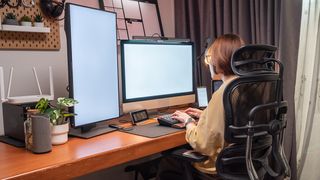 A woman sits on an ergonomic chair while typing on her keyboard. 