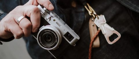Fujifilm X100V review: hand holding silver compact camera showing lens and front 