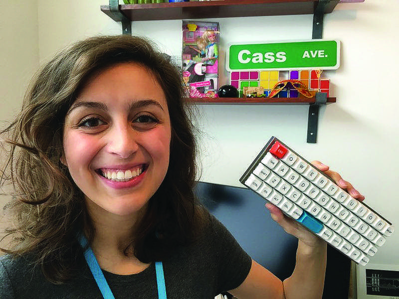 An image of Cassidy Williams smiling and holding up her Scrabble keyboard side project.