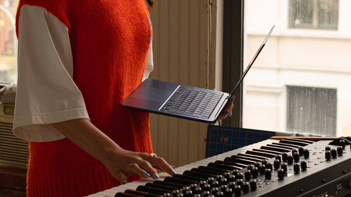 A woman holds a laptop and plays music