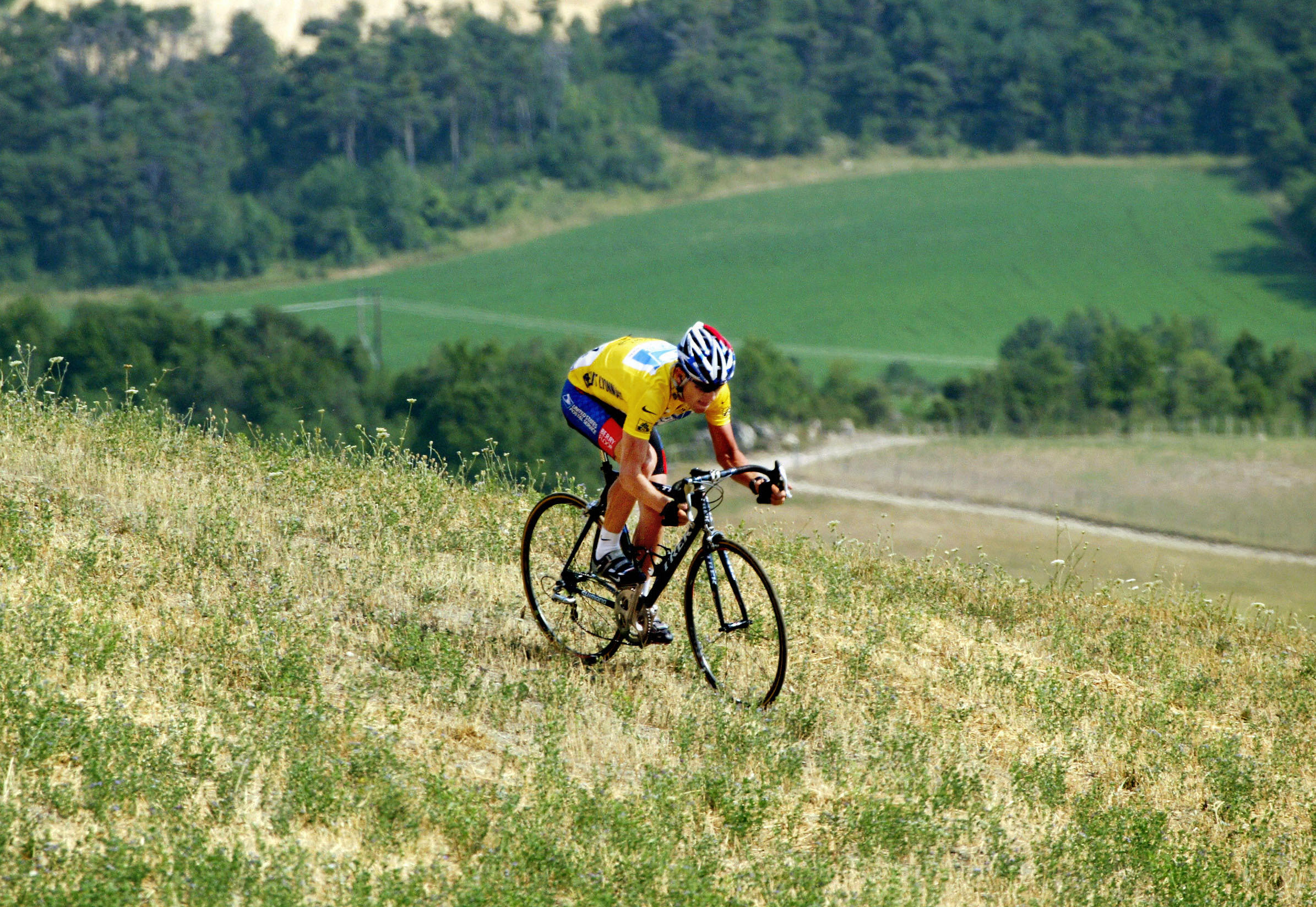 GAP, FRANCE: US Lance Armstrong (US Postal/USA) rides on the grass after avoiding Spaniard Joseba Beloki (ONCE/Spa) who fell down at the end of the ninth stage of the 90th Tour de France cycling race between Bourg d'Oisans and Gap, 14 July 2003. AFP PHOTO JOEL SAGET (Photo credit should read JOEL SAGET/AFP via Getty Images)