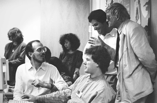 Adobe Creative Director Russell Brown (left, seated) with artists Nicholas Callaway (center, seated) and David Hockney (right, standing) and other colleagues at Adobe's Art Directors Invitational, 1990. Image Credit: Doug Menuez/Stanford University Libraries