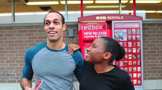 An image of two people standing in front of a Redbox return kiosk