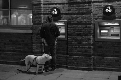 Man at cashpoint with white dog in black and white