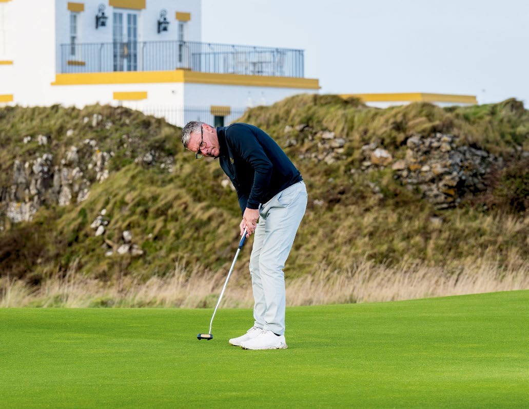 Steve North hitting a putt on a windy, exposed green at Trump Turnberry