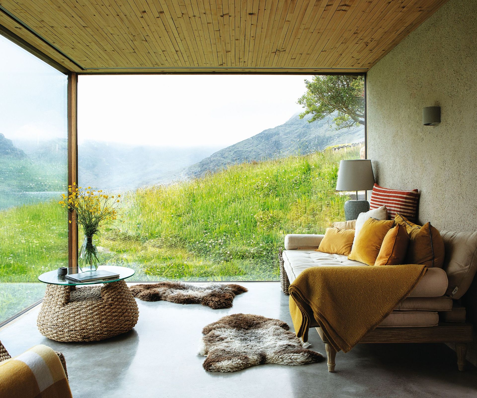 White sofa cushions, fur rugs, wicker and glass coffee table
