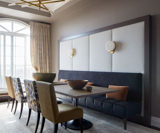 Large dining room space with cozy, navy, fabric bench seating and chairs across long wooden table