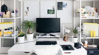 Home office with computer, plants, ideas board, stationery, printer, comfy chair
