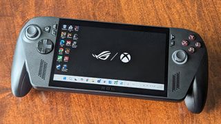 Xbox Ally X lying on its back on a table with the Windows desktop showing on its screen. 