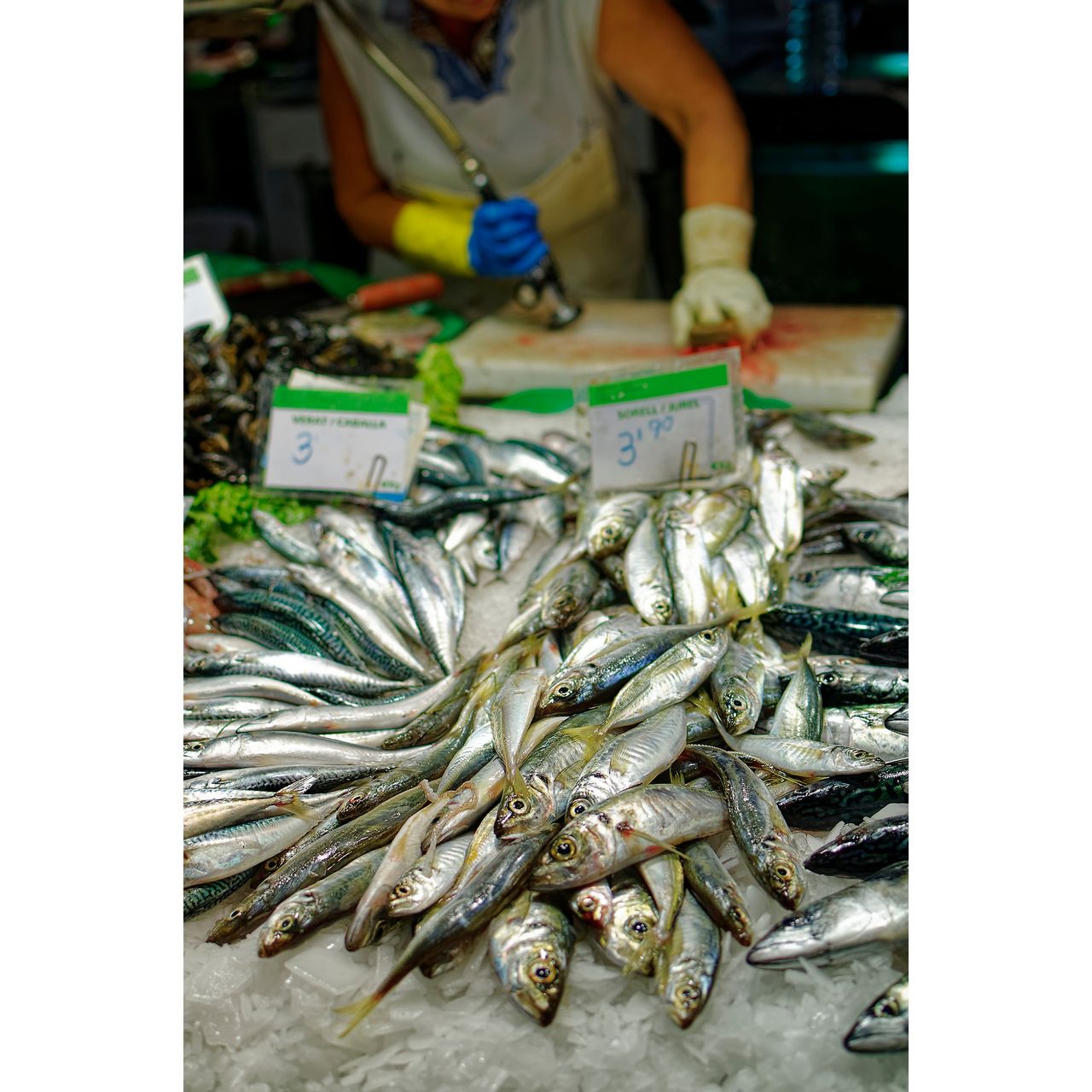 Fish counter at Barcelona&rsquo;s historic La Boqueria market, with fishmonger working in background