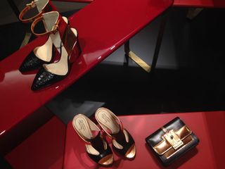 Black sandals and a leather purse displayed on a red counter