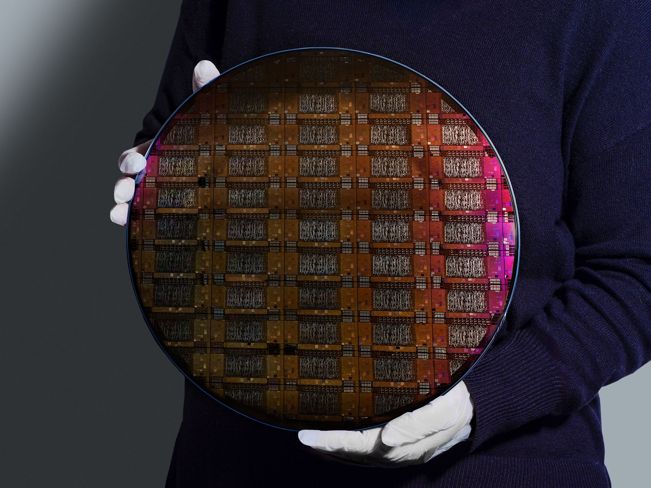 An IBM researcher holding a 300mm IBM Quantum Loon wafer