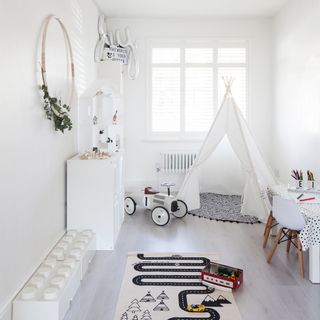 kids play area with white wall and white tent with toys