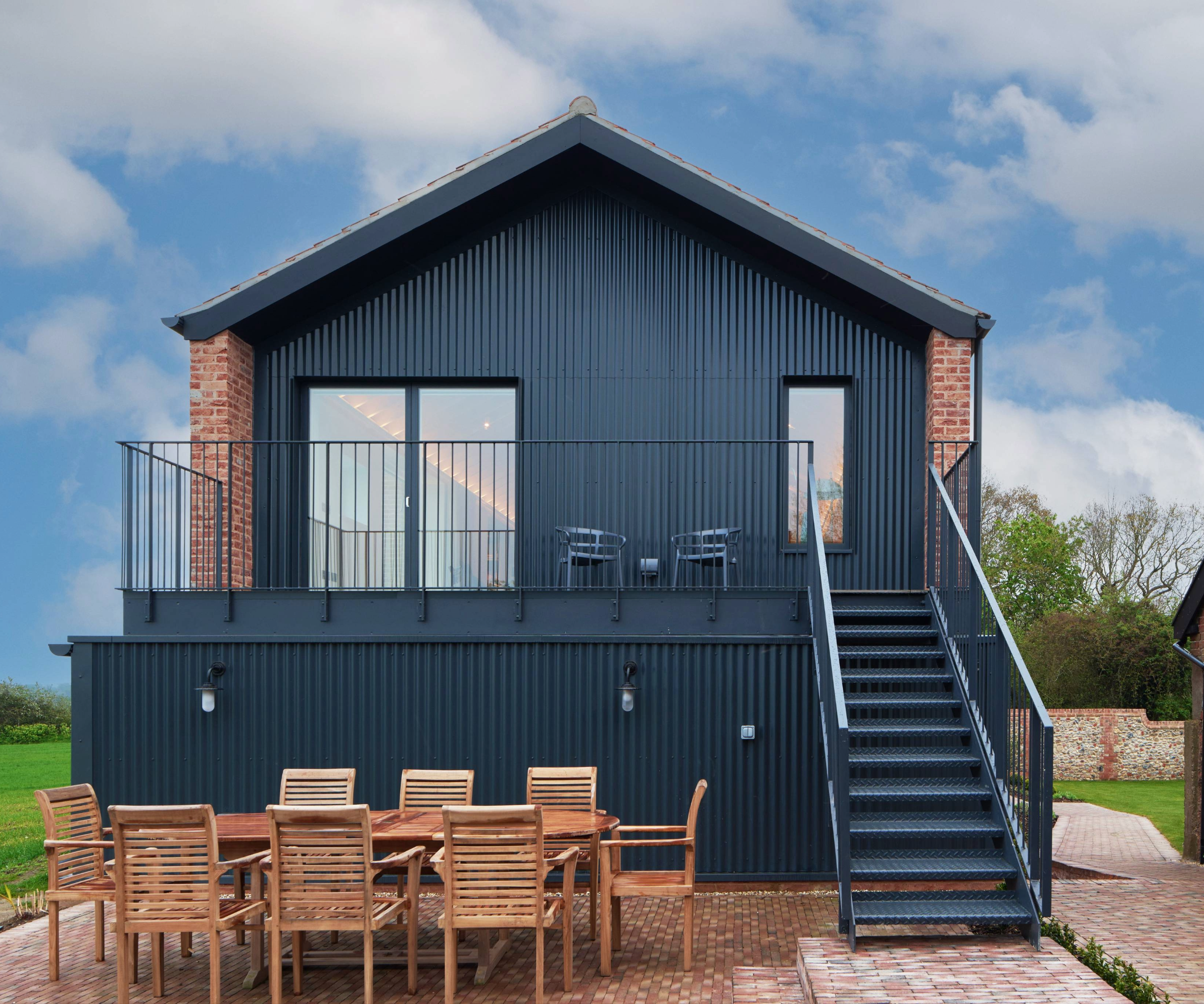 Side of the house with terrace area that has a staircase down to a ground level seating area