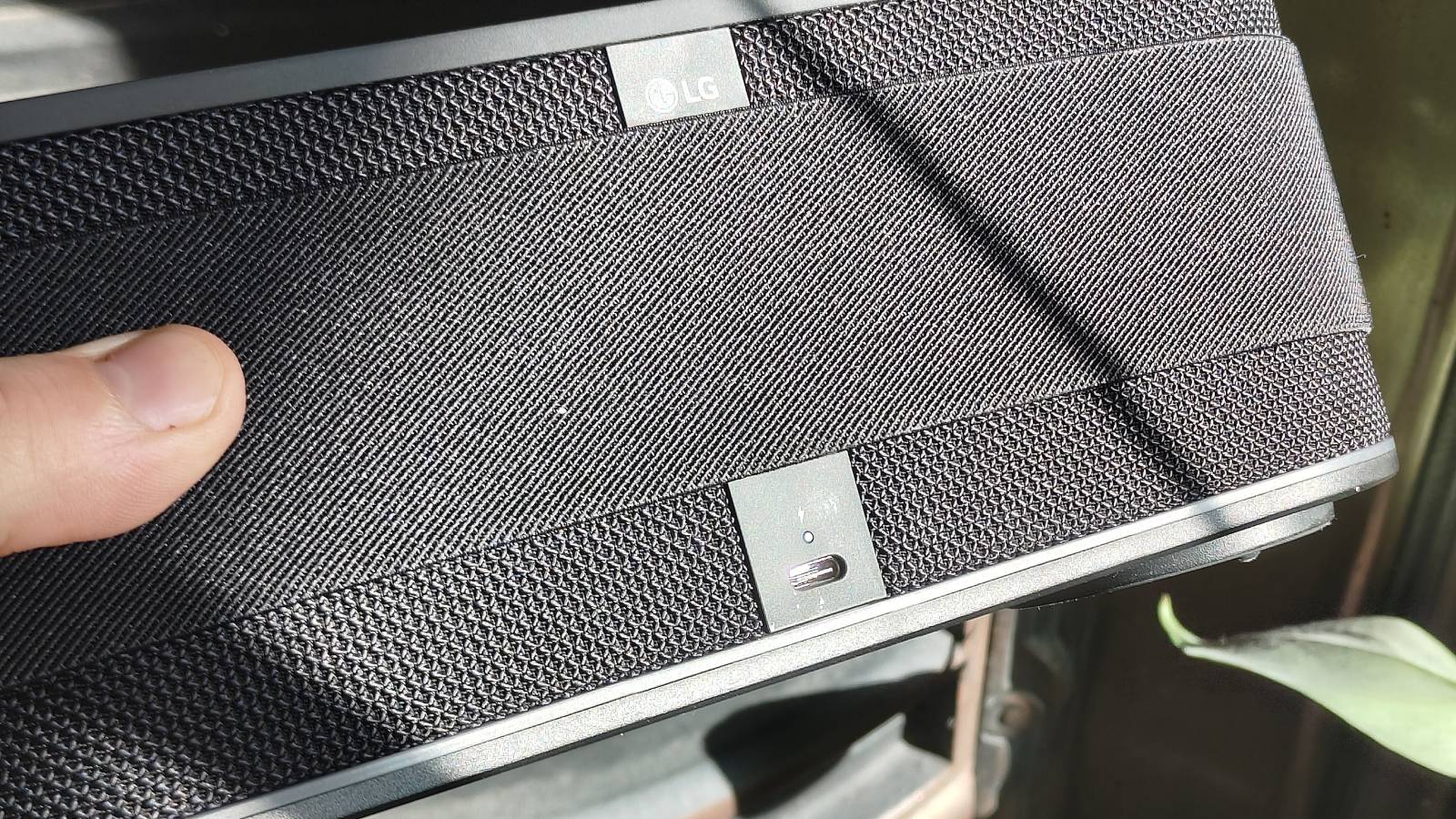 The LG xboom Bounce by a leafy plant on a shelf.