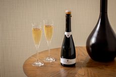 A bottle of Rathfinny Wine Estate's Mini Cuv&eacute;e 2020, the UK&rsquo;s first 50cl sparkling wine, on a table with two glasses