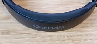 A pair of black and grey OneOdio A10 headphones sitting on a wooden desk