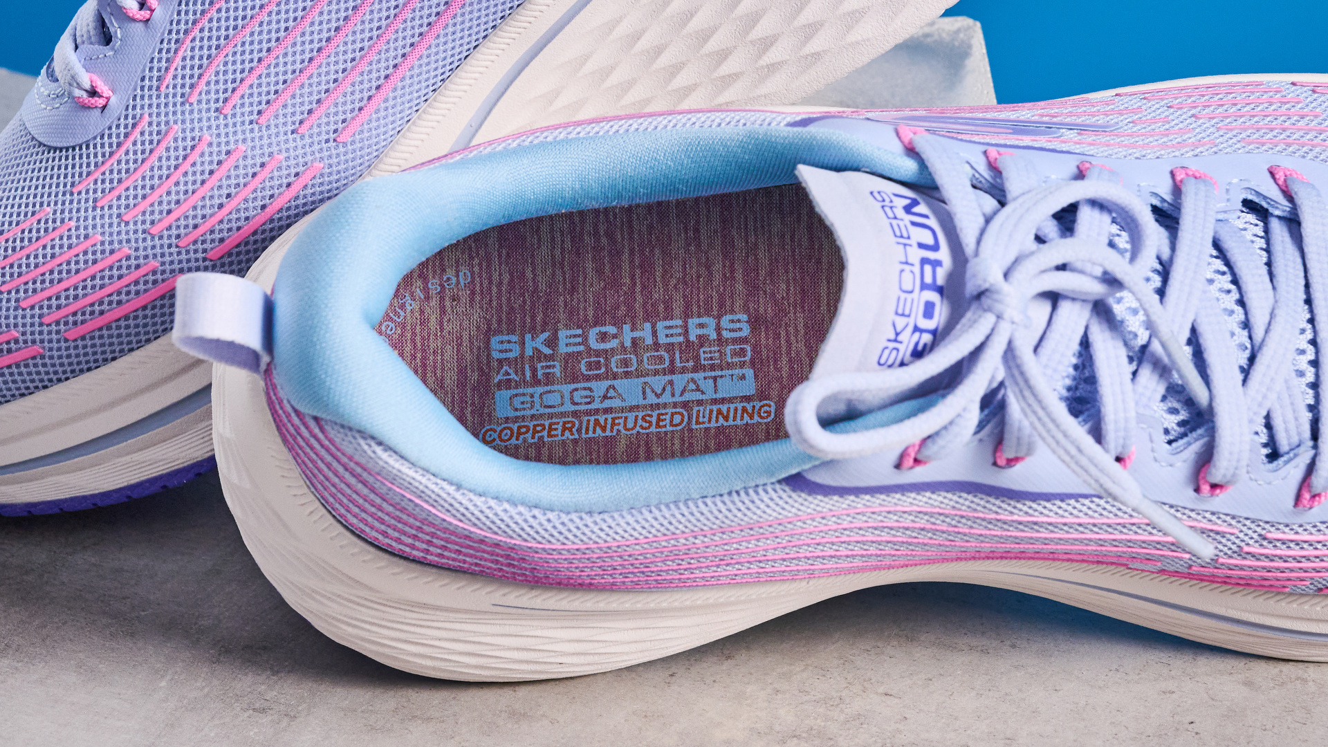 Skechers Max Cushioning Elite 2.0 running shoes photographed in front of a blue background.