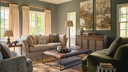 A green living toom, with a cream two-seater sofa, a green sofa opposite it, and a leather-topped coffee table in the center of them. 