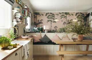 A shaker style DeVol kitchen with pink patterned wallpaper and built-in seating.