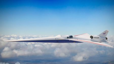 a white and blue jet with an elongated nose soars through clouds