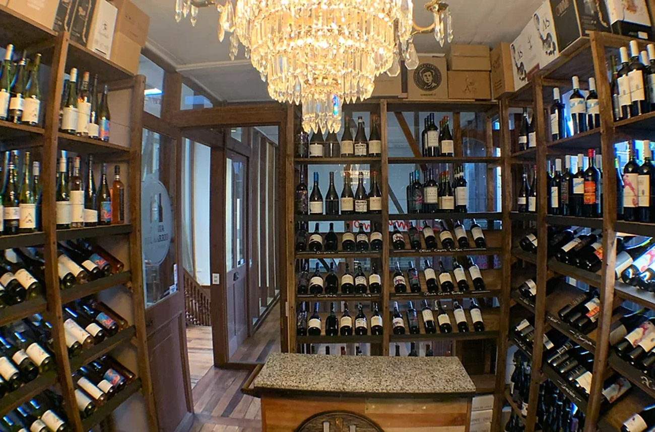 Shelves of wine bottles in a wine shop with a chandelier in the ceiling