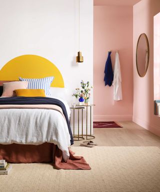bed in pink bedroom with yellow paint arch feature