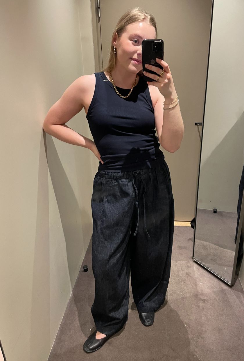 Woman wears navy tank top, denim trousers and ballet flats