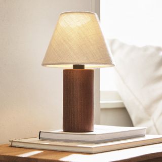Wooden lamp with linen lampshade on bedside table