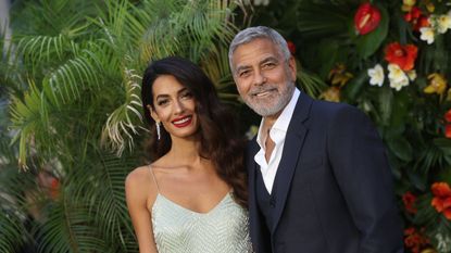 george and amal clooney together against a background of tropical plants