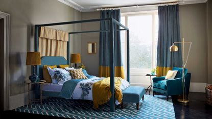 blue and mustard bedroom with four poster and armchair