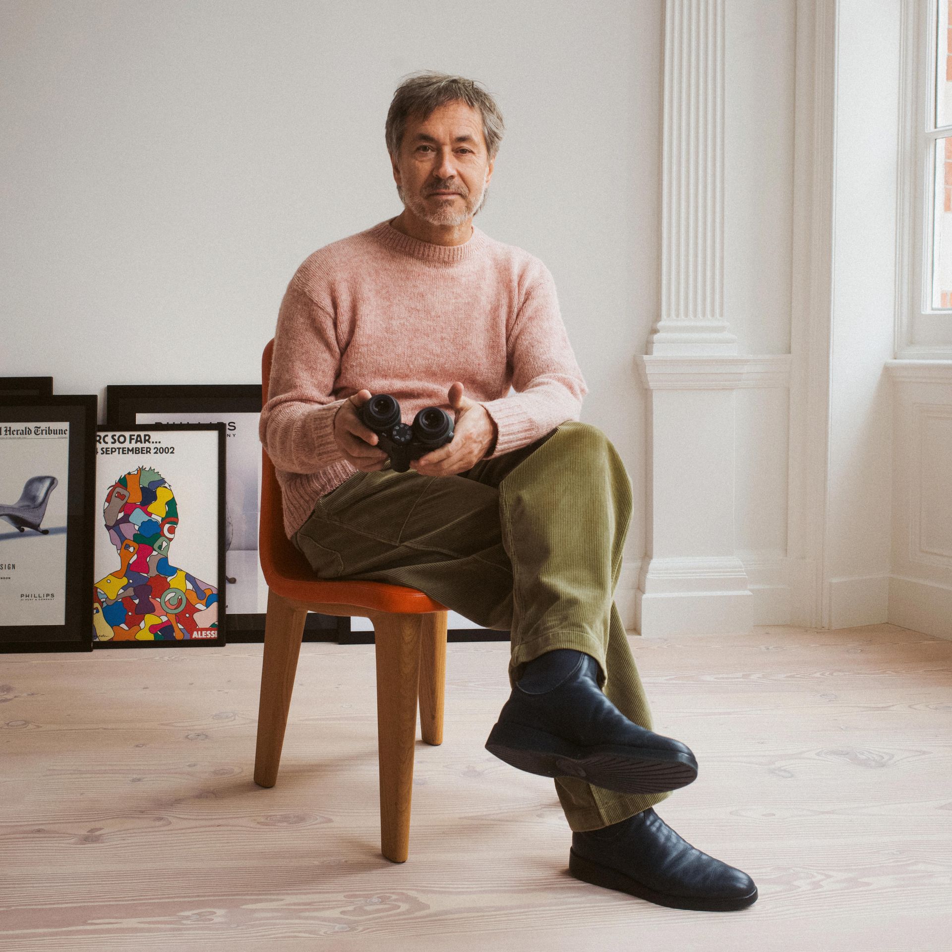 Marc Newson seated, holding binoculars
