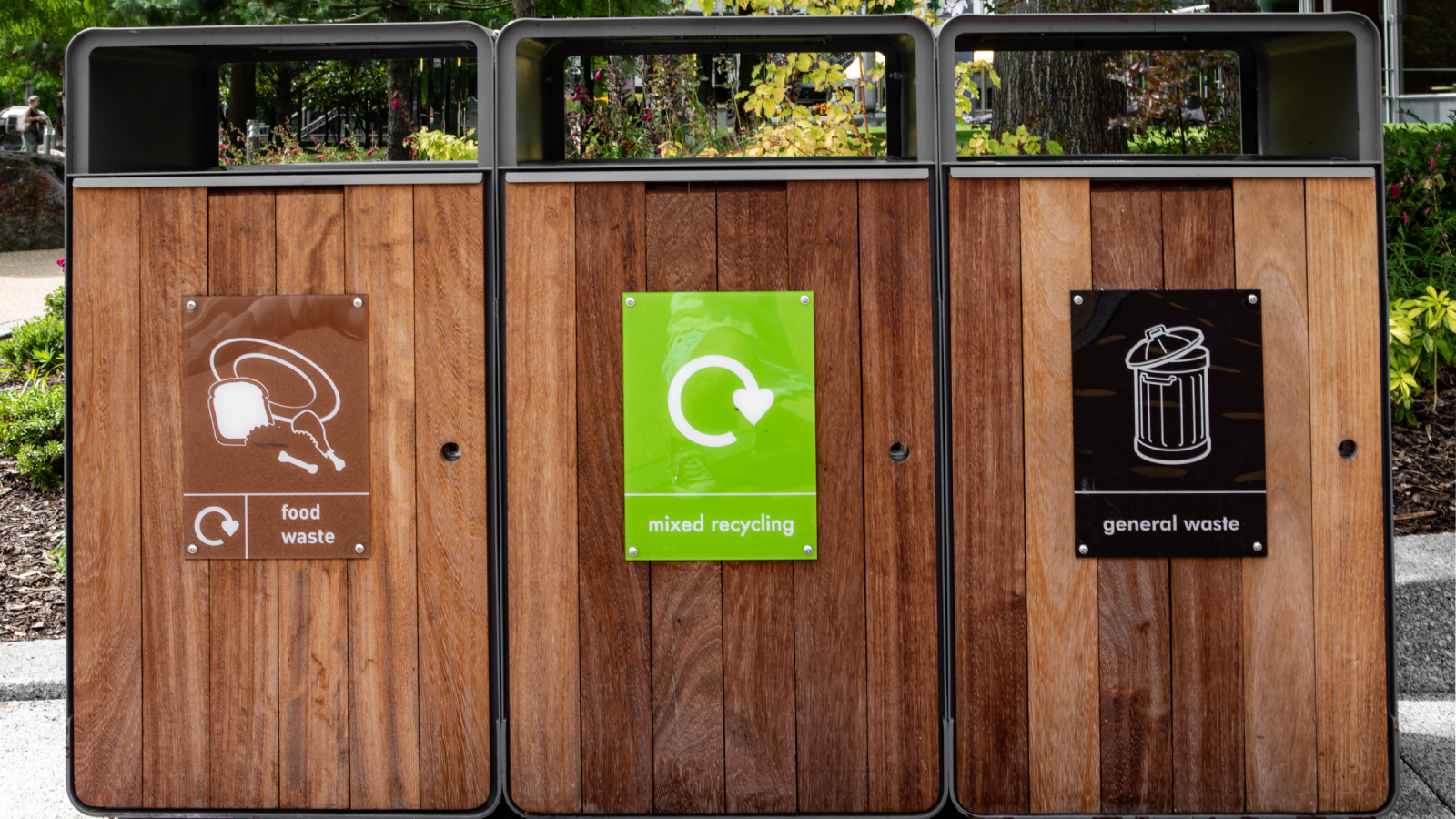 three large wooden recycling bins with signs identifying waste catgegory