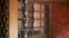 Traditional rain chain drainage system featuring series of connected cup-shaped or funnel-shaped metal containers