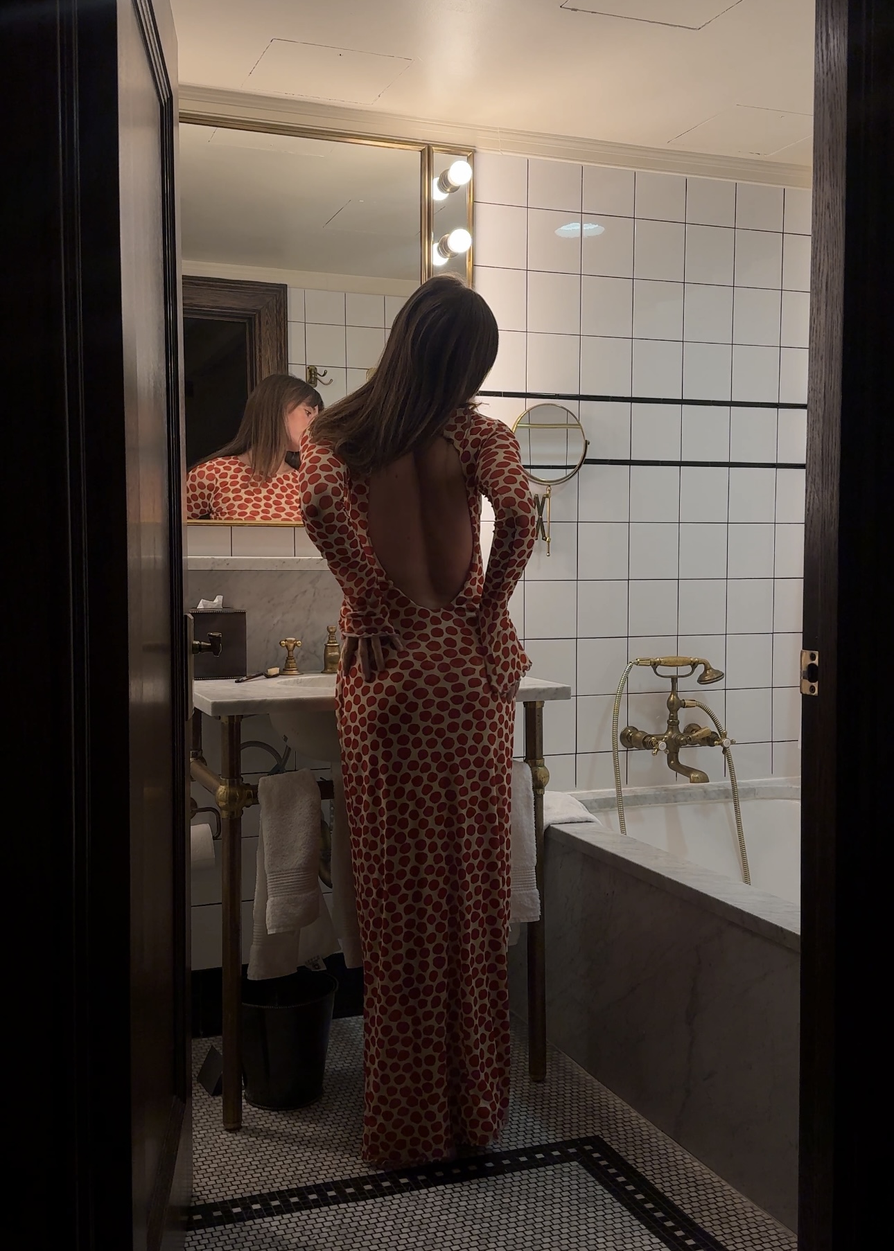 Kathryn Zahorak in bathroom wearing red polka dot backless dress