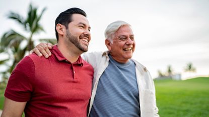 Father and adult son talking while walking on public park