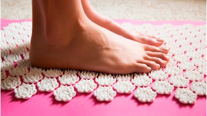 Female feet standing on acupressure mat - stock photo