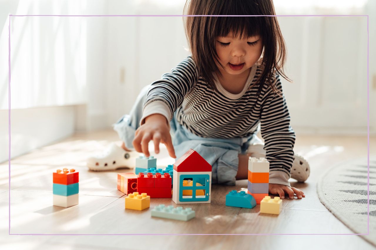 A young girl playing with toy blocks on the floor